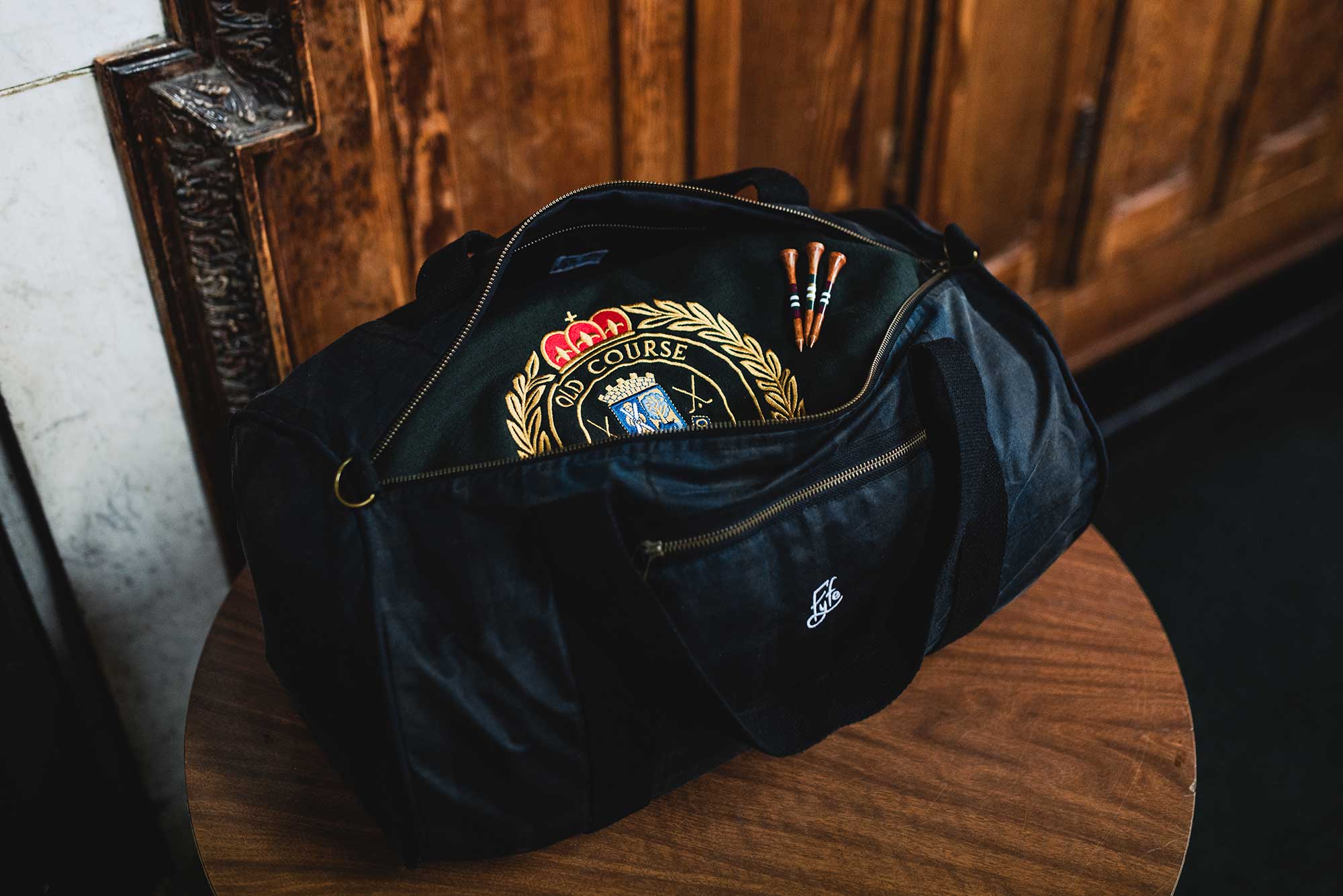 Waxed Duffel bag inside a golf clubhouse locker room – A premium duffel bag placed in a classic golf clubhouse locker room, highlighting its refined design and craftsmanship, with wooden lockers in the background, evoking a sense of tradition and elegance.